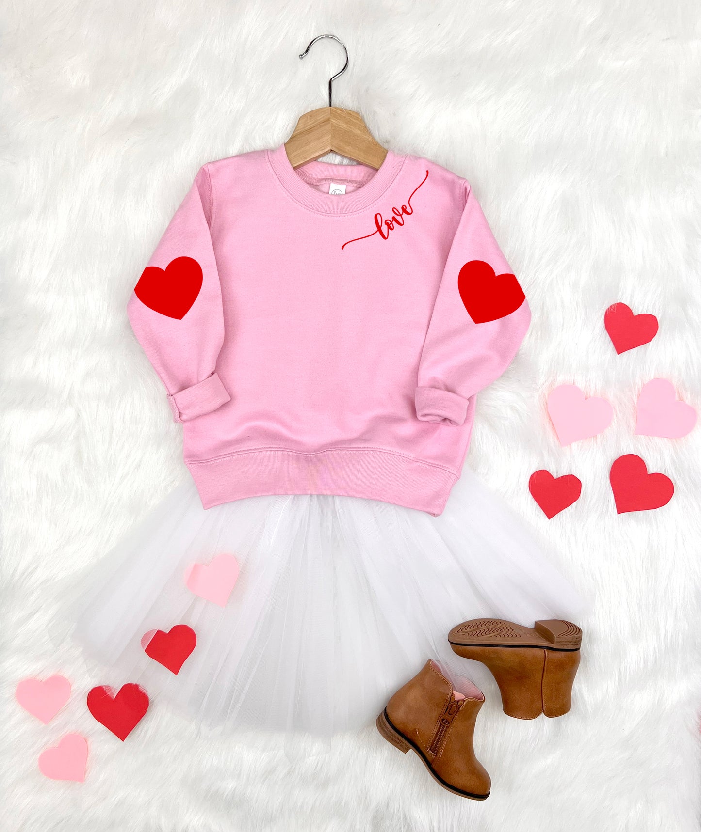 Pink sweatshirt with red hearts and 'love' text, white tutu, brown boots on a white background.