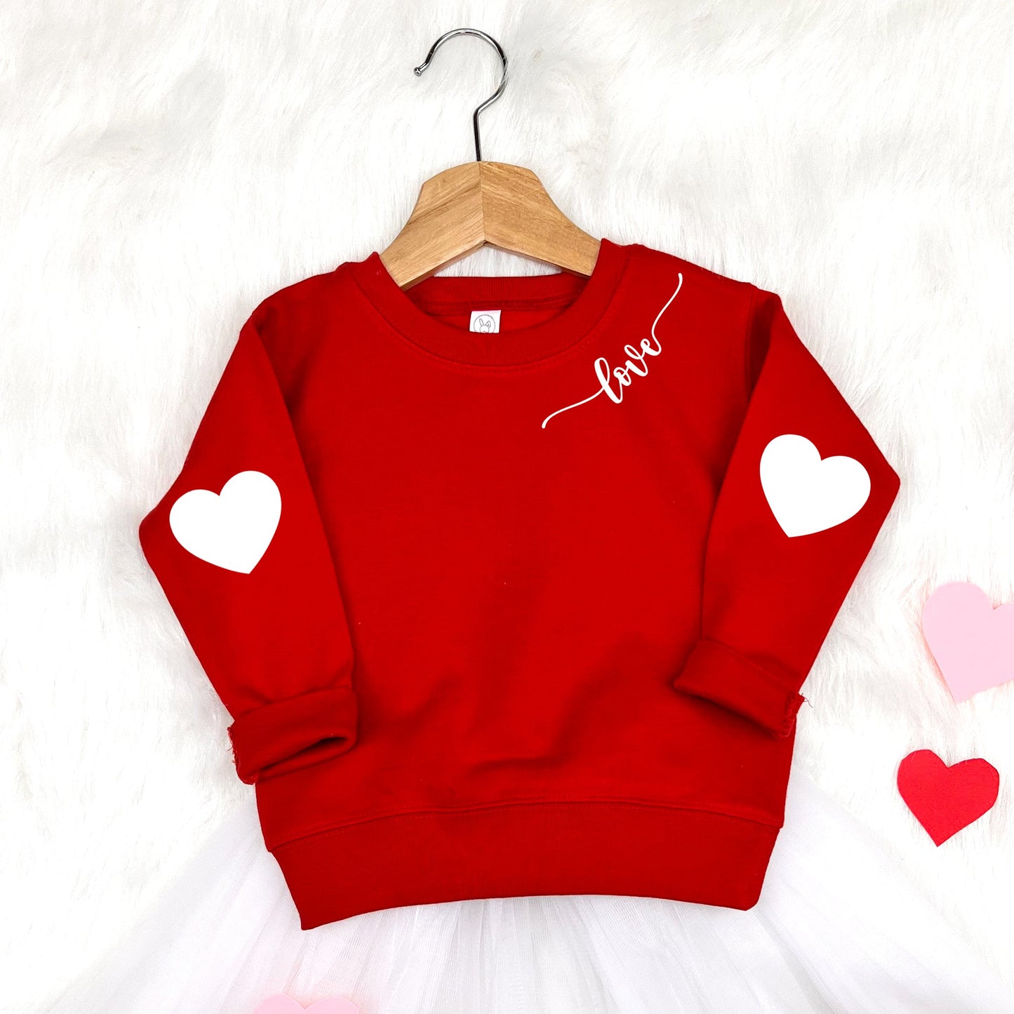 This adorable children’s sweatshirt is a best-selling favorite, featuring cute printed heart elbow "patches" and a delicate “love” script detail by the neck, for a timeless Valentine’s-inspired look. Made for comfort and everyday wear, it’s perfect for toddlers and kids to wear for Valentine’s Day, photos, school, or cozy outings. A charming, stylish sweatshirt that parents love and kids feel great wearing. 
