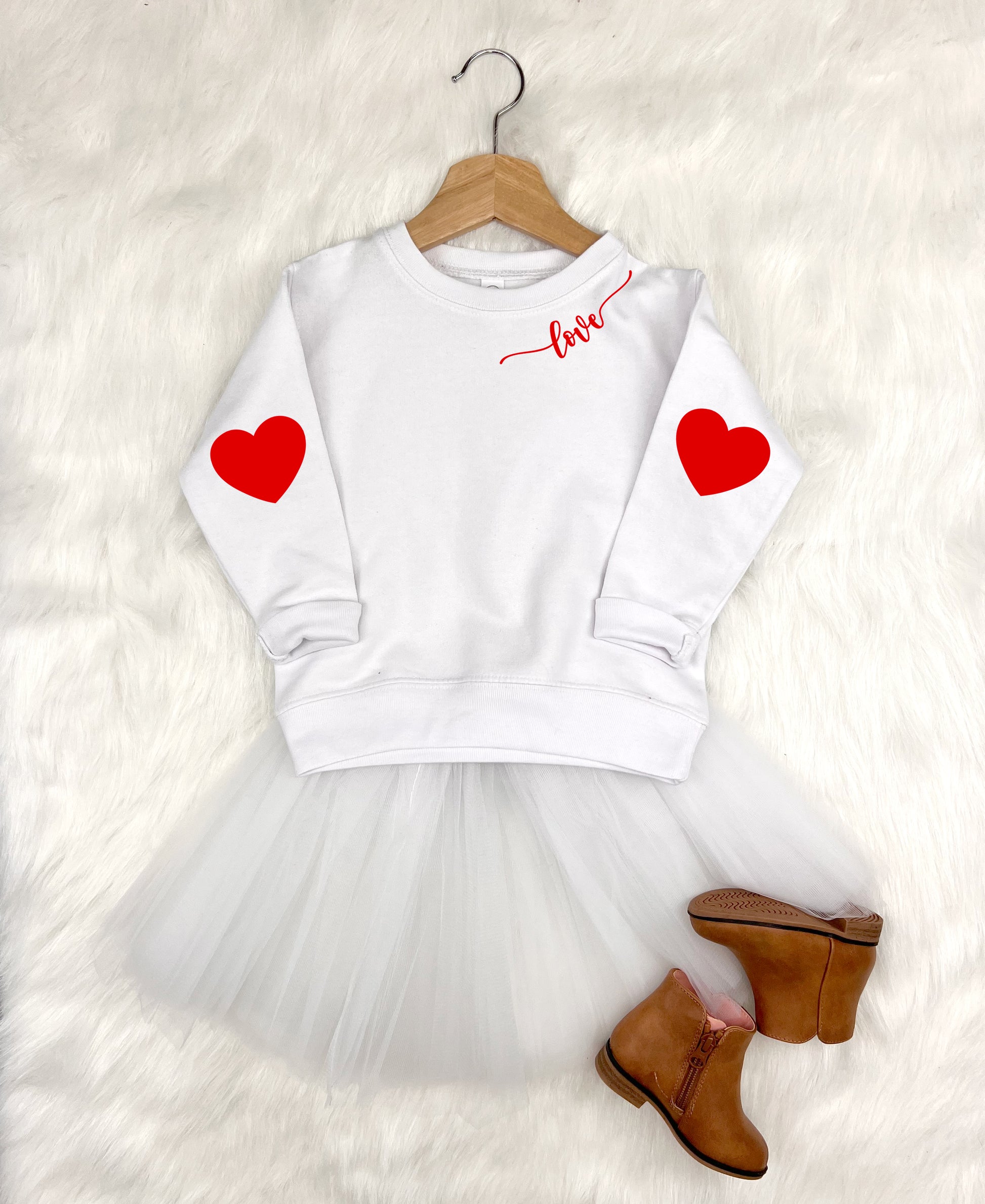 White sweatshirt with red hearts and a tutu skirt on a white background